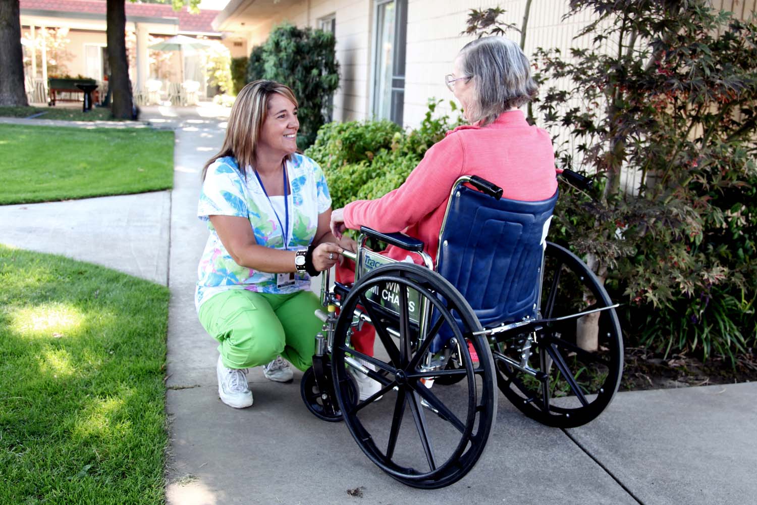 Nurse squatting and smiling at person in wheel chair