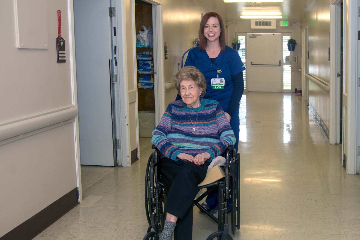 Nurse pushing person in wheel chair.