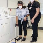 Nurse assisting with hand extension tool to pick up item off the floor